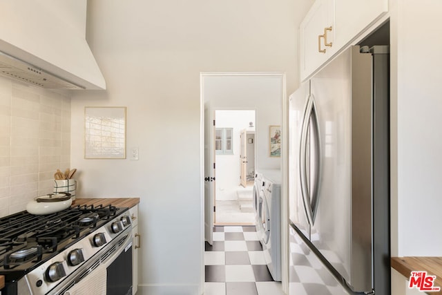 kitchen with appliances with stainless steel finishes, tasteful backsplash, ventilation hood, separate washer and dryer, and white cabinetry