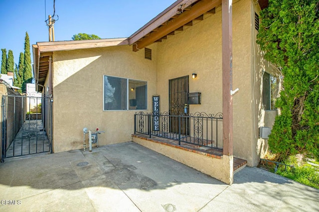 rear view of property featuring a gate, a patio, and stucco siding