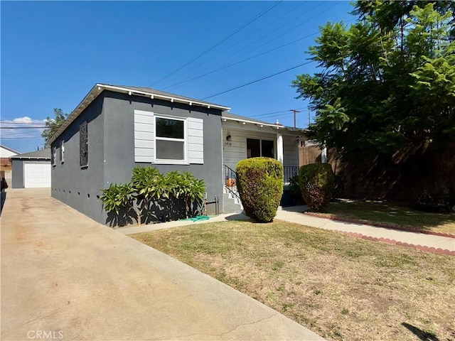 view of front facade with a front yard, an outbuilding, and a garage