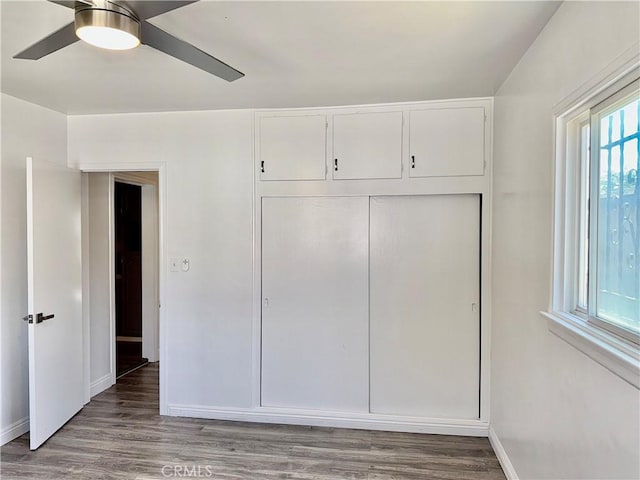 unfurnished bedroom featuring hardwood / wood-style flooring, ceiling fan, and a closet