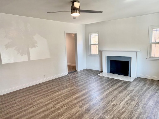 unfurnished living room featuring a wealth of natural light, ceiling fan, and dark hardwood / wood-style floors