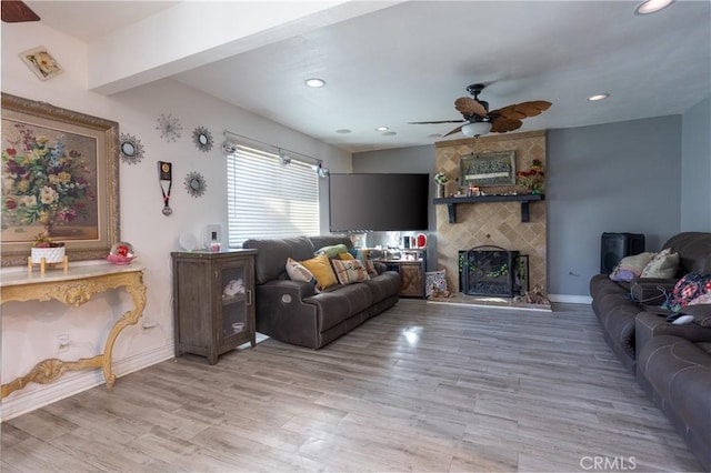 living room featuring ceiling fan, a fireplace, and wood-type flooring