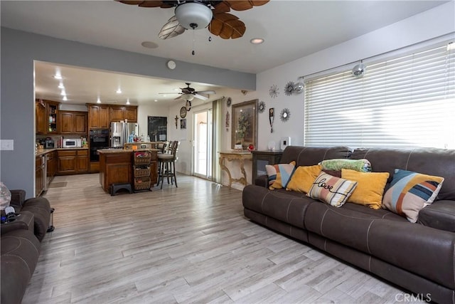 living room with plenty of natural light, ceiling fan, and light wood-type flooring