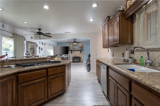 kitchen featuring light stone countertops, stainless steel appliances, ceiling fan, sink, and light hardwood / wood-style floors