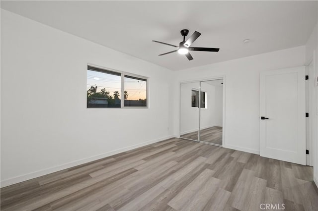 unfurnished bedroom with a closet, light hardwood / wood-style flooring, and ceiling fan