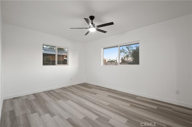 spare room with light hardwood / wood-style floors, a wealth of natural light, and ceiling fan