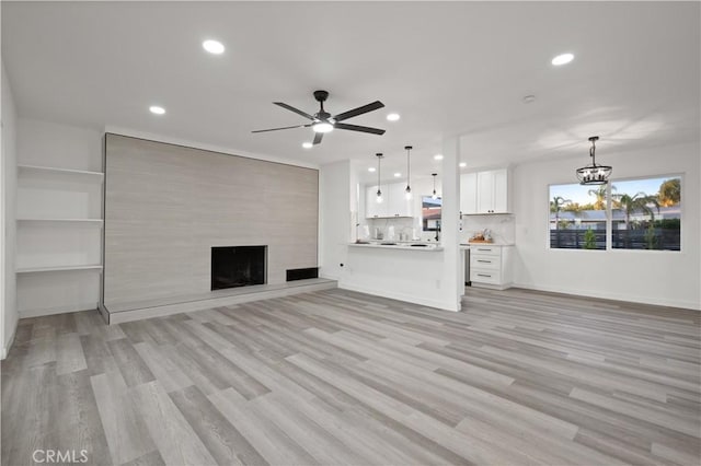 unfurnished living room featuring ceiling fan, light wood-type flooring, and a fireplace