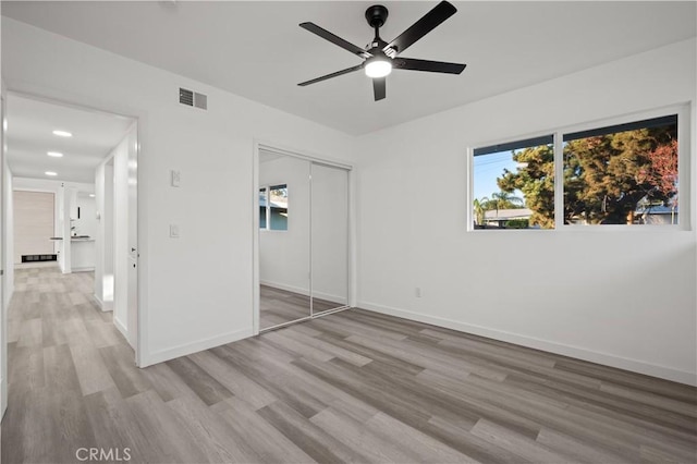 unfurnished bedroom with ceiling fan, light hardwood / wood-style flooring, and a closet