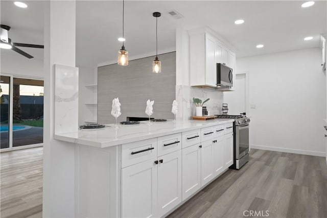 kitchen with kitchen peninsula, white cabinetry, light stone counters, and appliances with stainless steel finishes