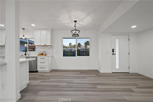 kitchen featuring dishwasher, white cabinets, tasteful backsplash, and hanging light fixtures