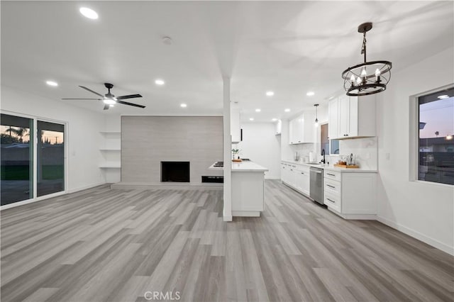 kitchen featuring white cabinetry, dishwasher, pendant lighting, ceiling fan with notable chandelier, and light wood-type flooring