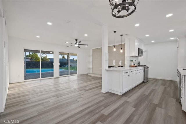 kitchen with white cabinetry, hanging light fixtures, light hardwood / wood-style floors, and ceiling fan with notable chandelier