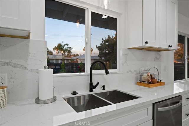 kitchen featuring white cabinetry, light stone countertops, sink, and stainless steel dishwasher