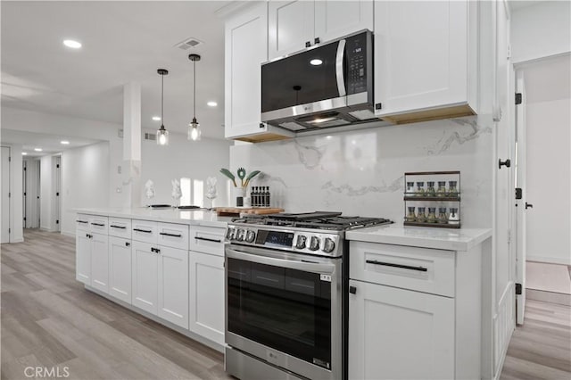 kitchen with white cabinetry, backsplash, decorative light fixtures, appliances with stainless steel finishes, and light wood-type flooring