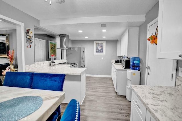 kitchen with ventilation hood, light wood-type flooring, light stone counters, white cabinetry, and stainless steel appliances