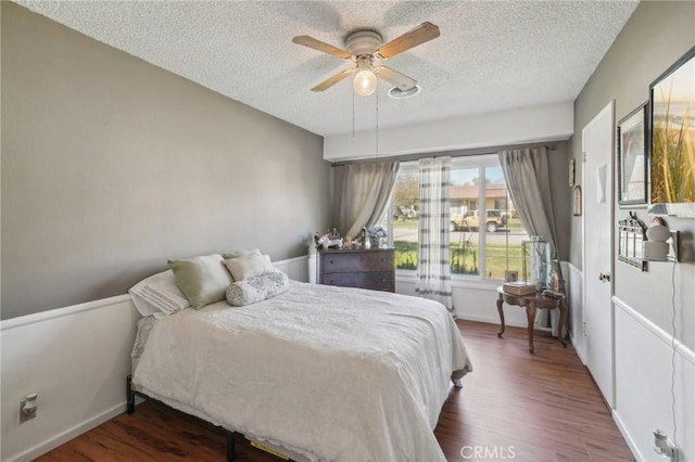 bedroom with ceiling fan, dark hardwood / wood-style floors, and a textured ceiling