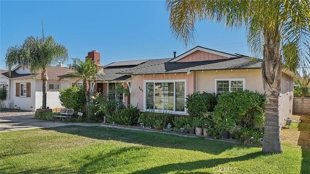 view of front of property with solar panels and a front lawn