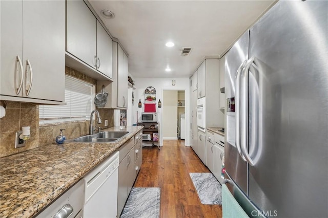 kitchen featuring stone counters, sink, tasteful backsplash, dark hardwood / wood-style floors, and white appliances