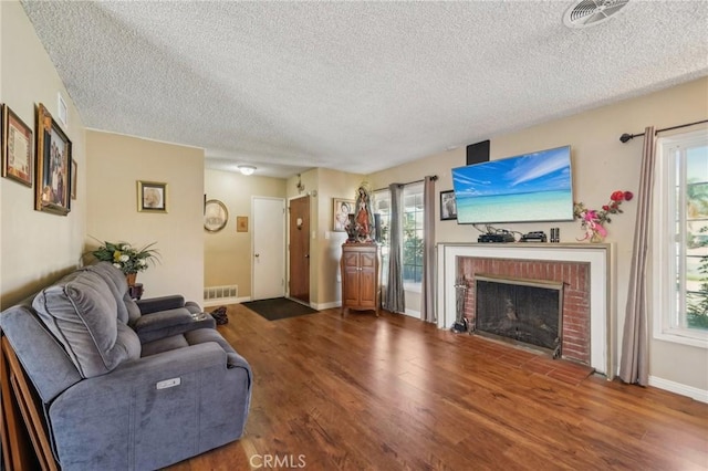 living room featuring a fireplace, a textured ceiling, and hardwood / wood-style flooring