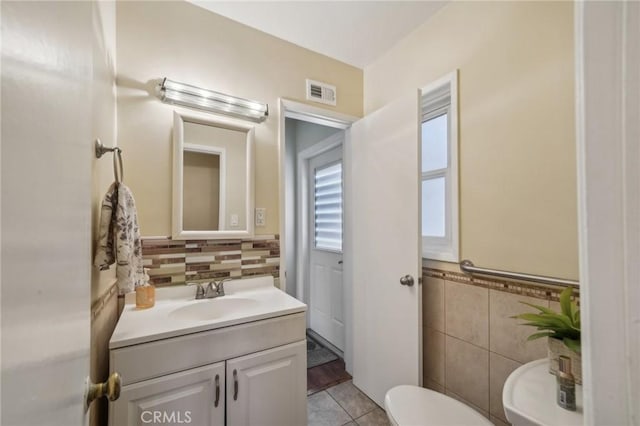 bathroom featuring tile patterned flooring, vanity, toilet, and tile walls