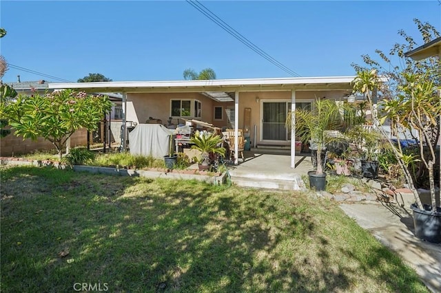 back of property with a lawn and a patio