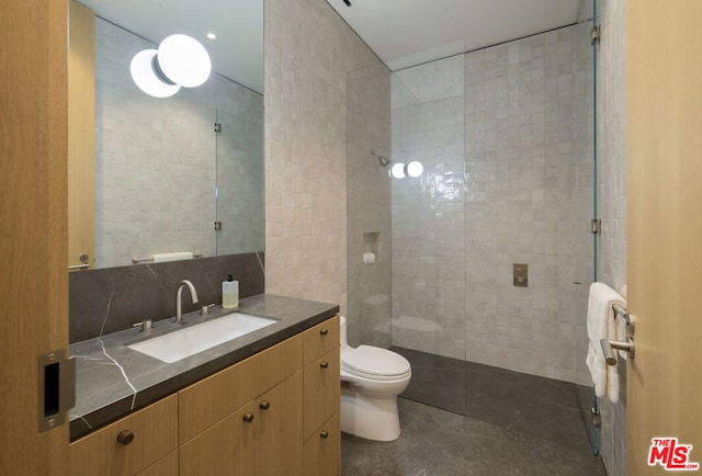 bathroom with tile patterned floors, a tile shower, toilet, and tile walls