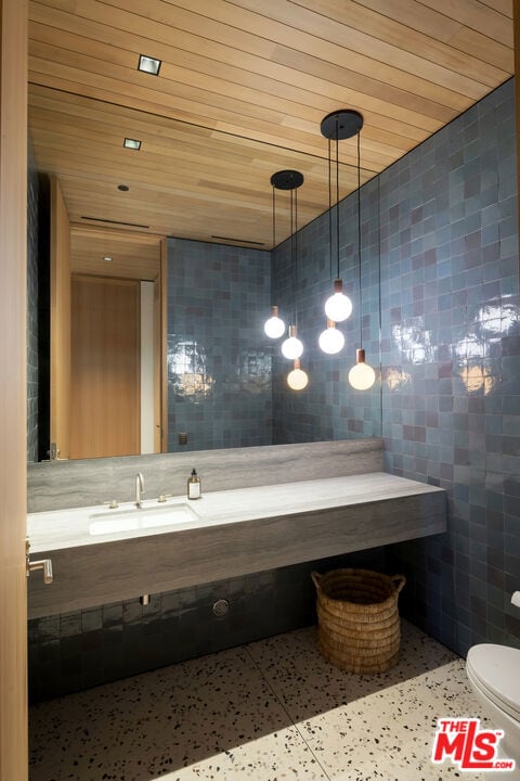 bathroom with sink, wooden ceiling, tile walls, and toilet