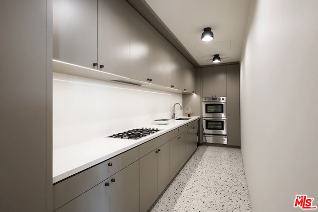 kitchen featuring gray cabinets, white gas stovetop, stainless steel double oven, and sink