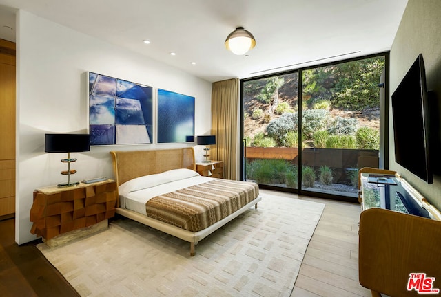 bedroom featuring access to exterior, expansive windows, and light wood-type flooring