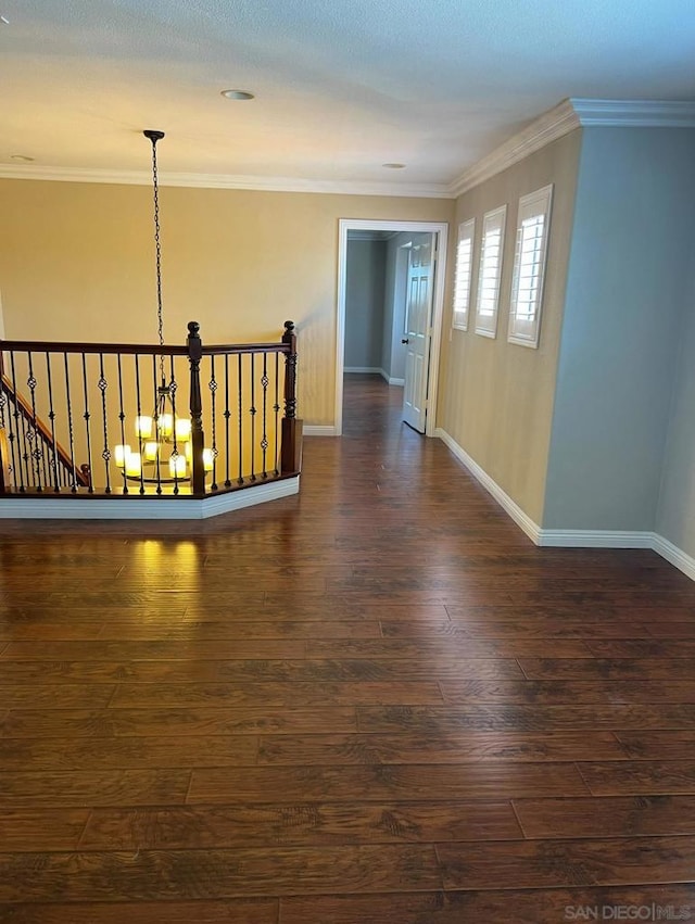 corridor with a notable chandelier, dark hardwood / wood-style floors, and ornamental molding