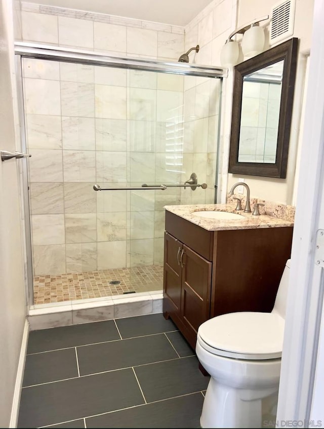 bathroom featuring tile patterned flooring, vanity, toilet, and a shower with shower door