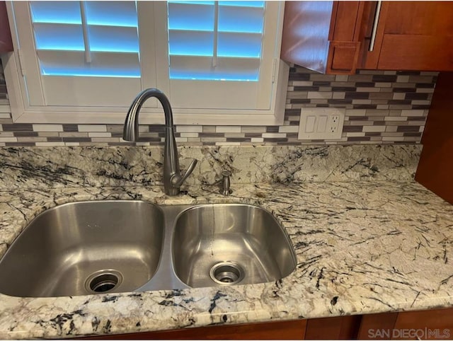 details featuring decorative backsplash, light stone counters, and sink