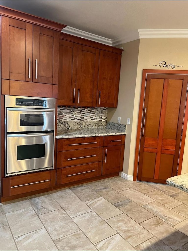 kitchen featuring decorative backsplash, light stone counters, crown molding, and double oven