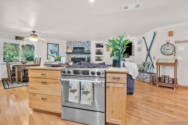 kitchen with ceiling fan, light brown cabinetry, built in features, and high end stove