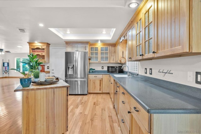 kitchen with light hardwood / wood-style floors, light brown cabinetry, stainless steel fridge, a tray ceiling, and crown molding