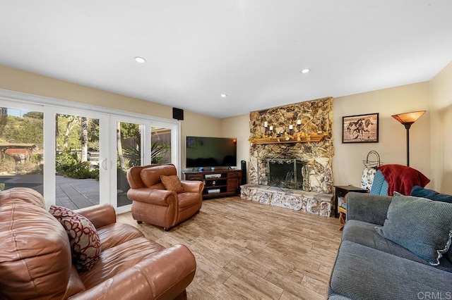 living area with recessed lighting, a stone fireplace, and wood finished floors