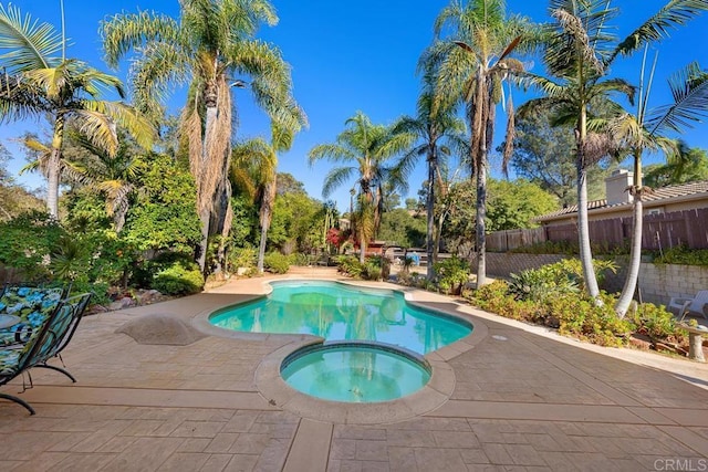 view of swimming pool featuring a patio area, fence, and a pool with connected hot tub