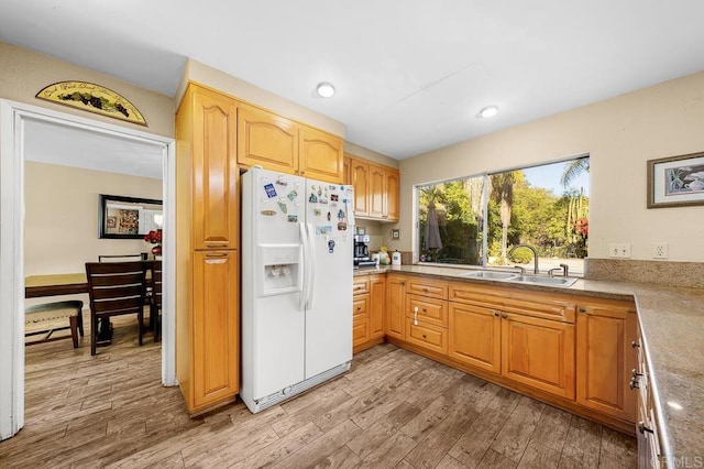 kitchen featuring light wood-style floors, white refrigerator with ice dispenser, light countertops, and a sink