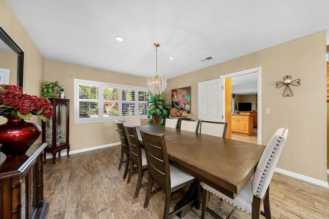 dining space featuring a chandelier, visible vents, baseboards, and wood finished floors