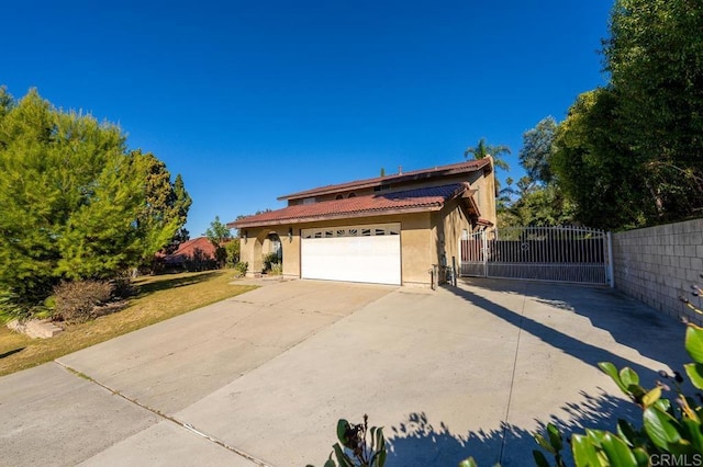 view of property exterior with fence, a tile roof, concrete driveway, a gate, and stucco siding