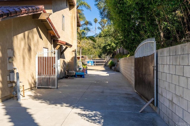 view of side of home with fence, a gate, and stucco siding