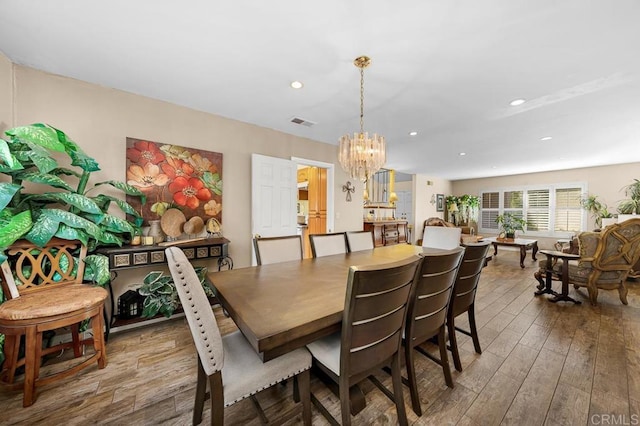 dining area with a chandelier, wood finished floors, visible vents, and recessed lighting