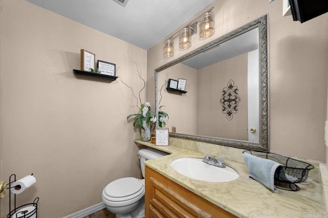 bathroom featuring baseboards, vanity, and toilet