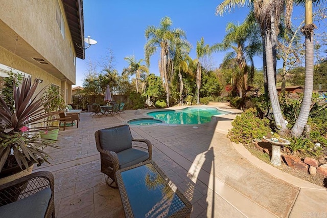 view of pool featuring a pool with connected hot tub, fence, and a patio