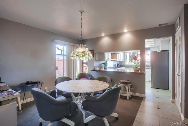 dining area featuring light tile patterned flooring, visible vents, and baseboards