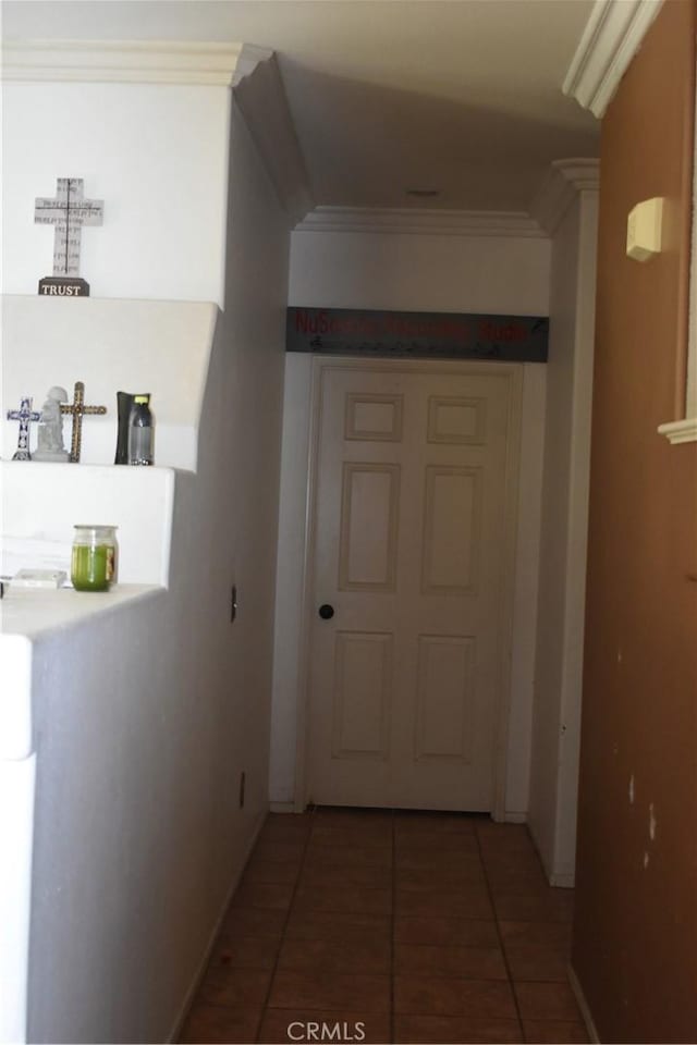 hallway with dark tile patterned flooring and crown molding