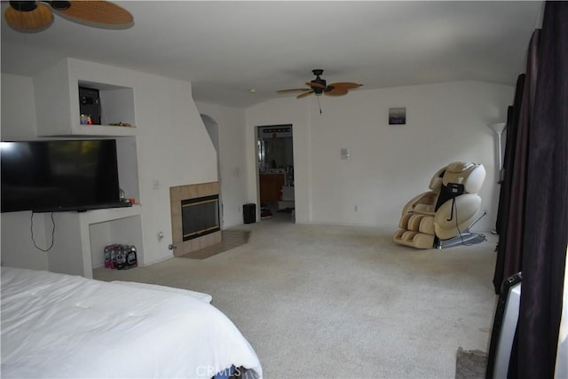 carpeted bedroom featuring ceiling fan and a fireplace