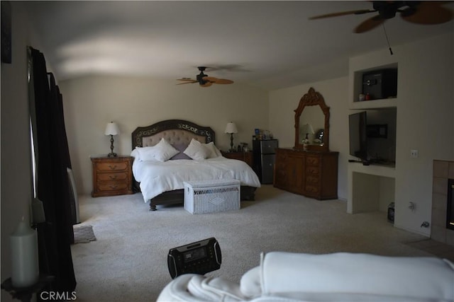 bedroom with ceiling fan, carpet, and a tiled fireplace