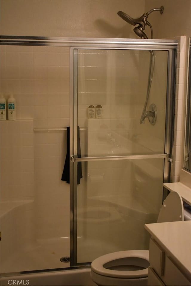 bathroom featuring toilet, a shower with shower door, and vanity