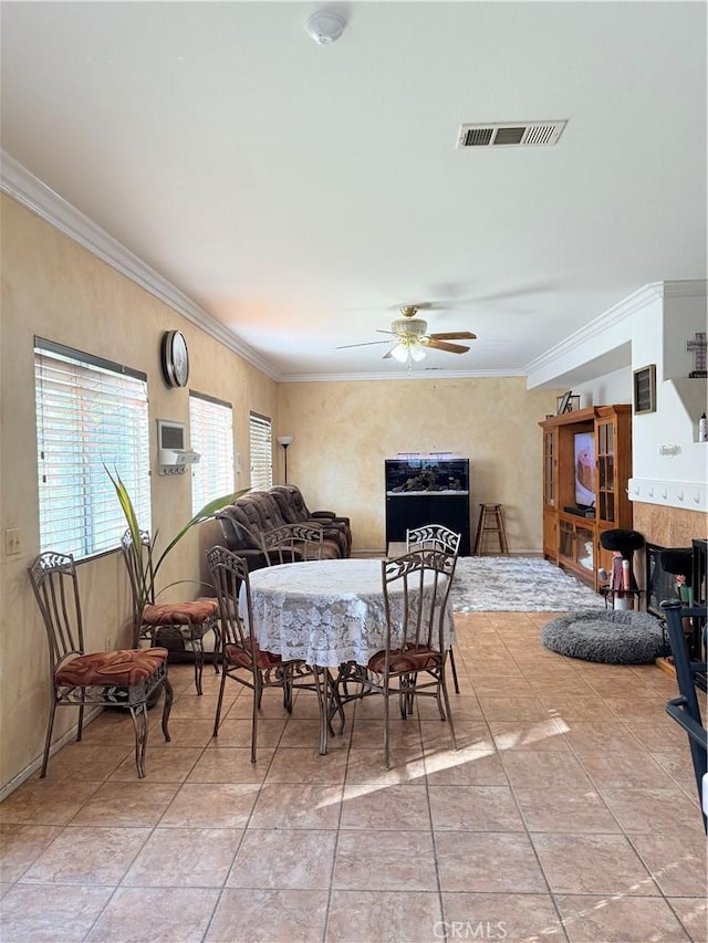 tiled dining room with ceiling fan and ornamental molding